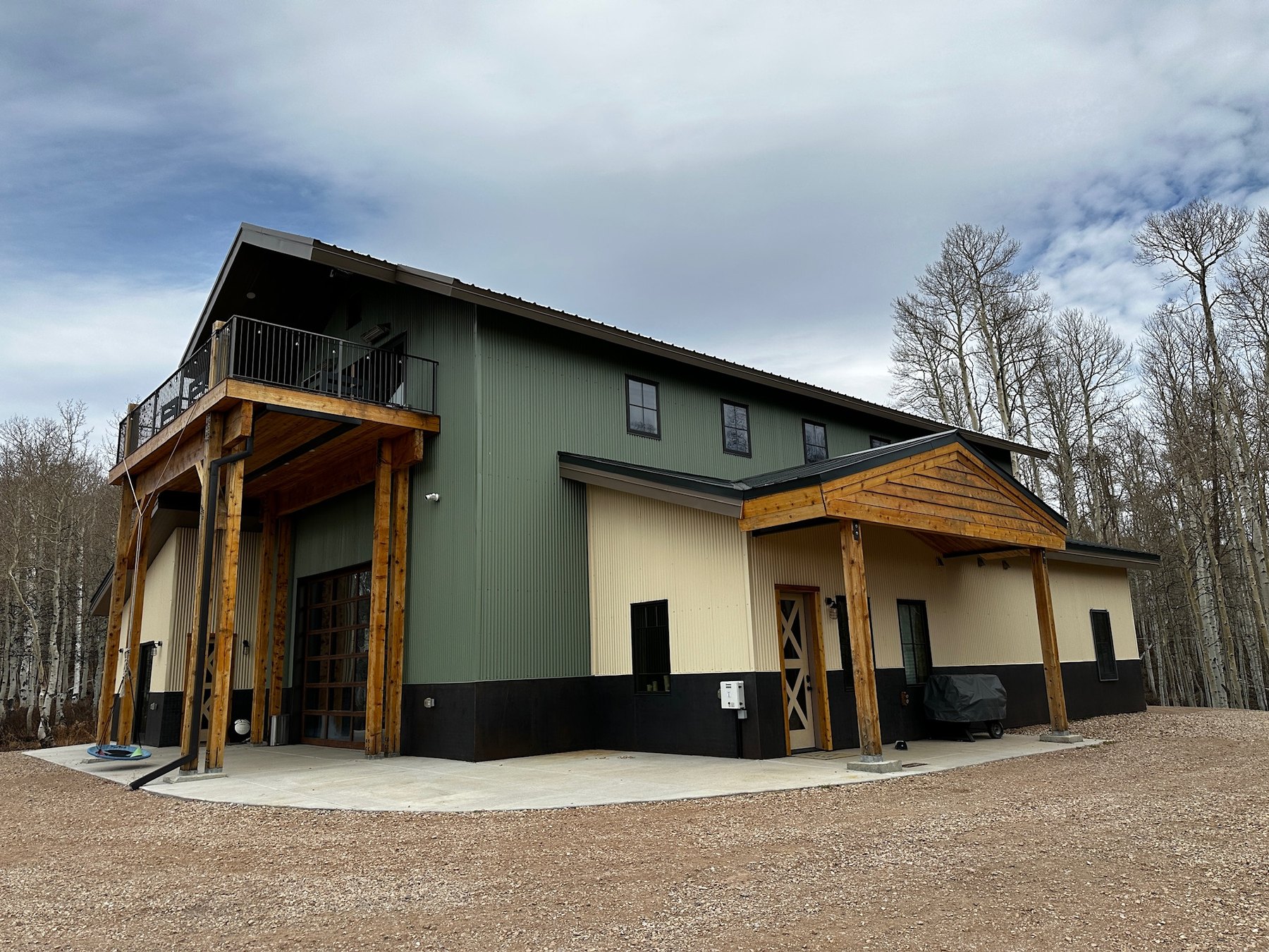 Custom timber-frame barn and shop with green and cream metal siding