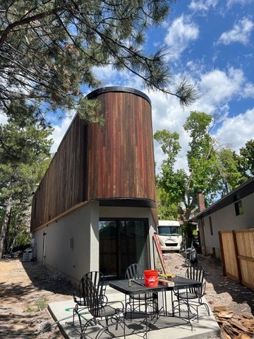 Finished curved cedar-clad building with steel balcony railing