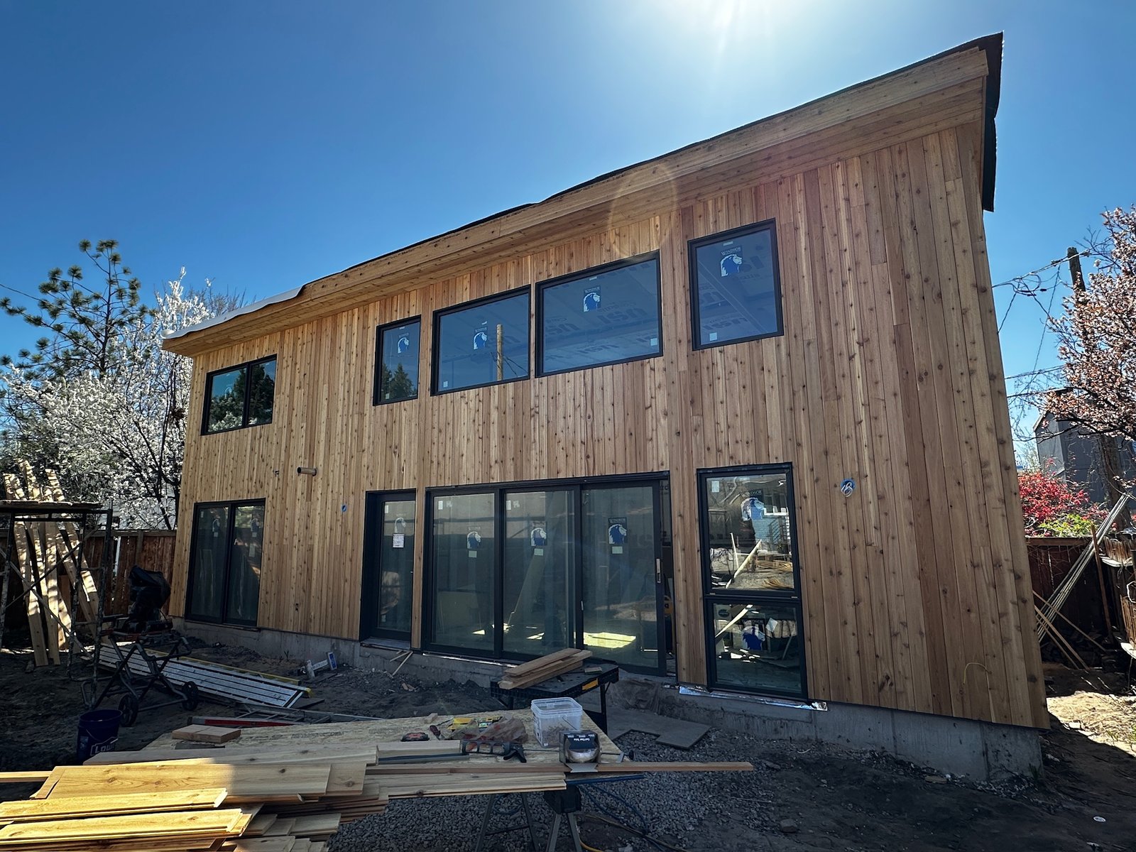 Modern custom home under construction with a dramatic angled shed roof and cedar siding